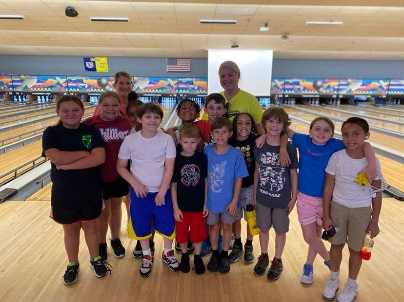 Group of kids and adults at bowling alley.