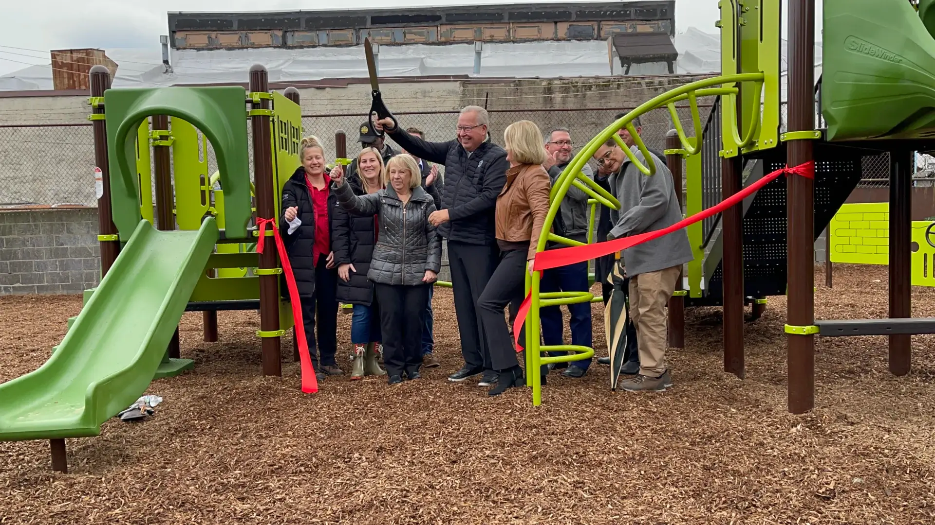 Group cutting ribbon at playground opening.