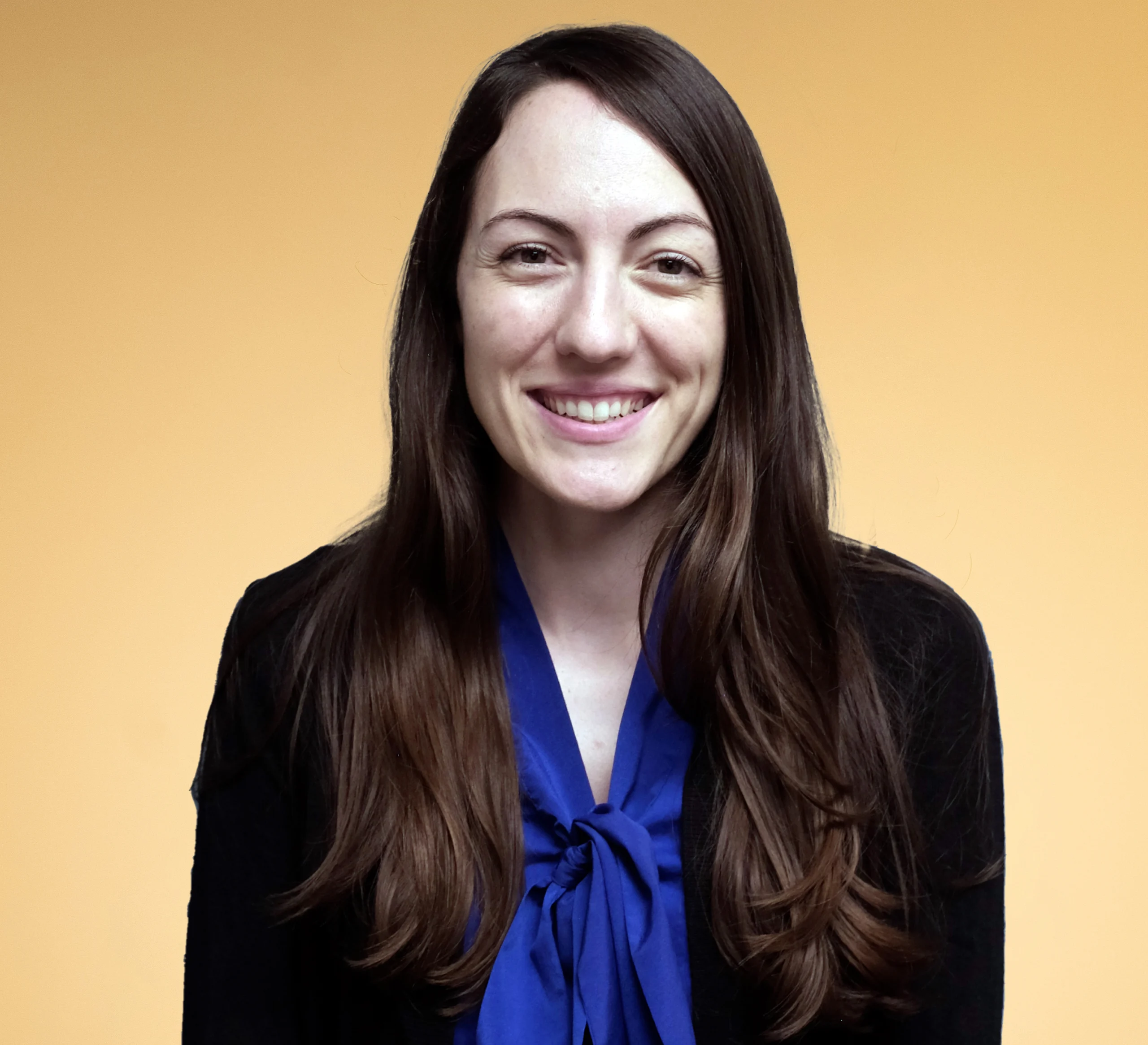 Smiling woman with long hair, orange background.