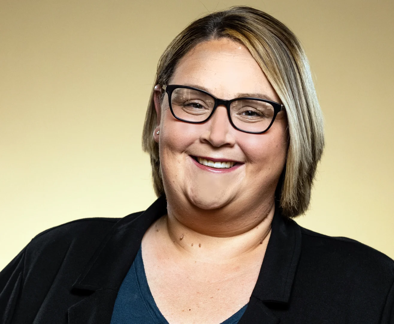 Smiling person wearing glasses and black jacket.