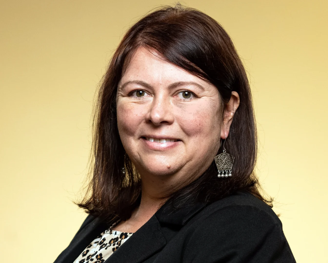 Smiling woman with brown hair, yellow background.
