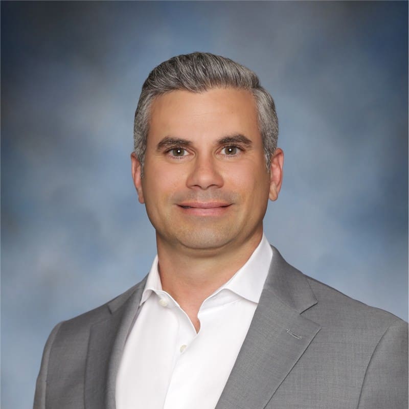Man in grey suit with neutral background.