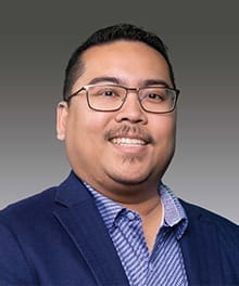 Man smiling in a suit and glasses.